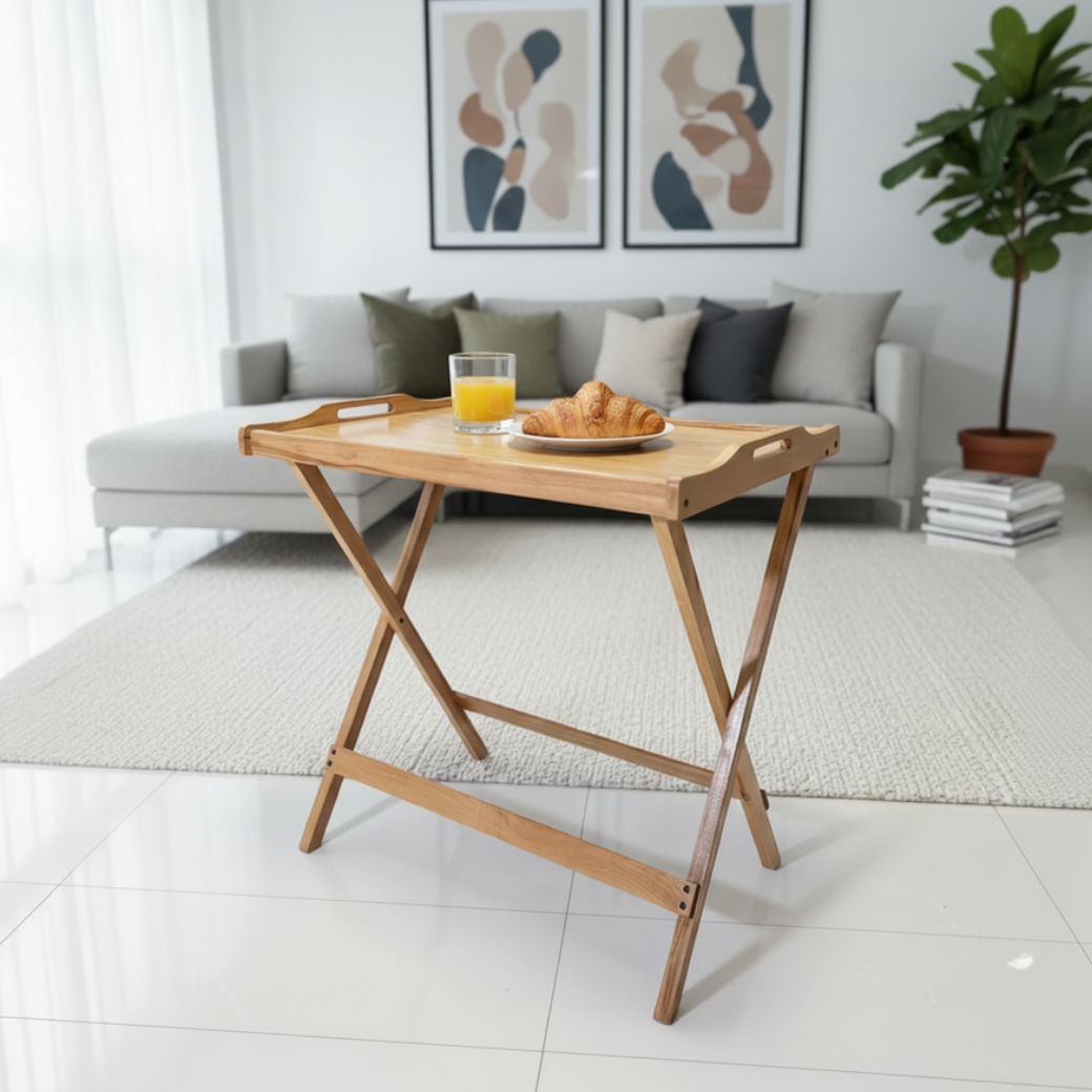 Wooden tray table with a glass of orange juice and a plate of croissants in a living room setting.