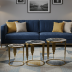 Modern living room with a blue sofa, gold coffee tables, and framed pictures on the wall.