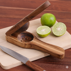 Wooden citrus press with limes and a knife on a wooden surface