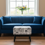 Blue sofa with a patterned ottoman in front of a window with flowers on the sill.