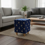 Blue patterned ottoman in a living room with gray sofas and a wooden coffee table.