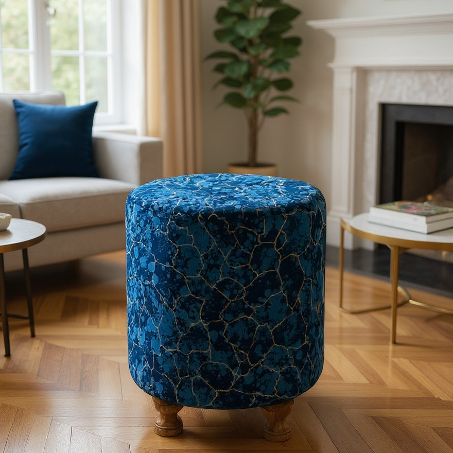 Blue patterned ottoman in a living room setting with a couch, coffee table, and plant.
