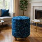Blue patterned ottoman in a living room setting with a couch, coffee table, and plant.