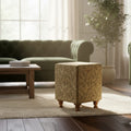 Living room with a textured ottoman, green sofa, and wooden coffee table.