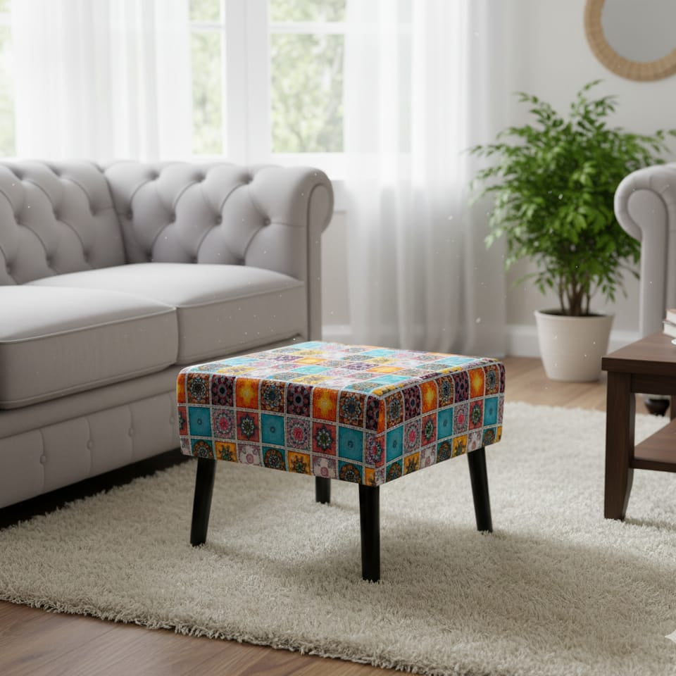Multicolored ottoman in a living room with a gray sofa and a plant.